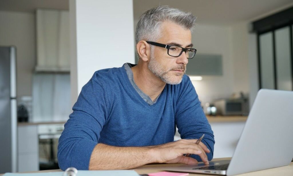 Mann sitzt vor dem Laptop.