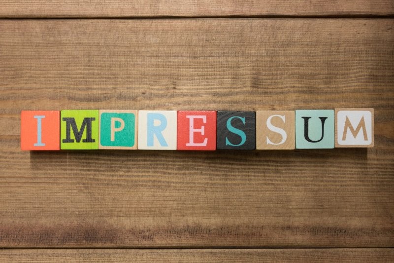 ‚Impressum‘ mit farbigen Buchstabenwürfeln dargestellt