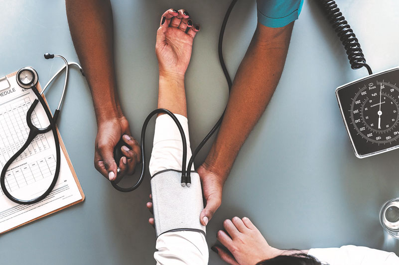 Eine Person misst den Blutdruck einer anderen Person. Nur die Arme sind zu sehen.