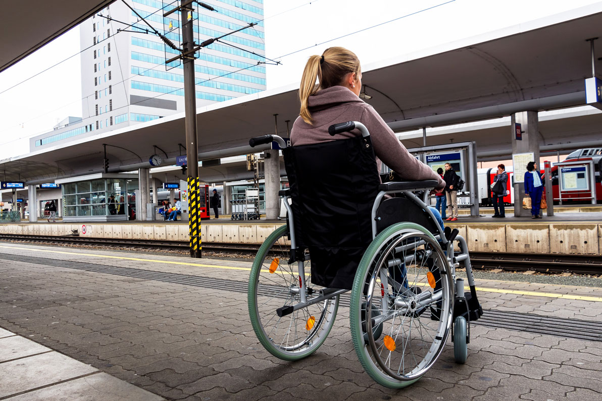 Une femme en situation de handicap attend sur un quai avant de prendre un train