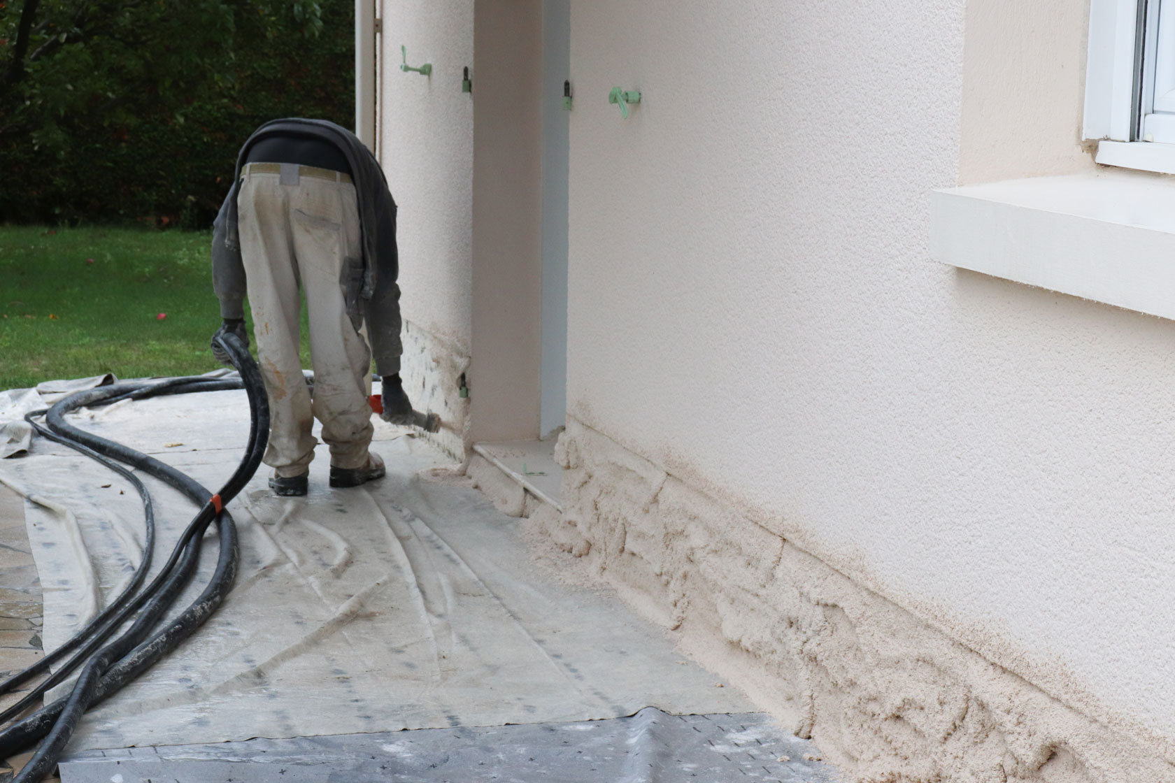 Un artisan réalise des travaux sur la face extérieure d'une maison