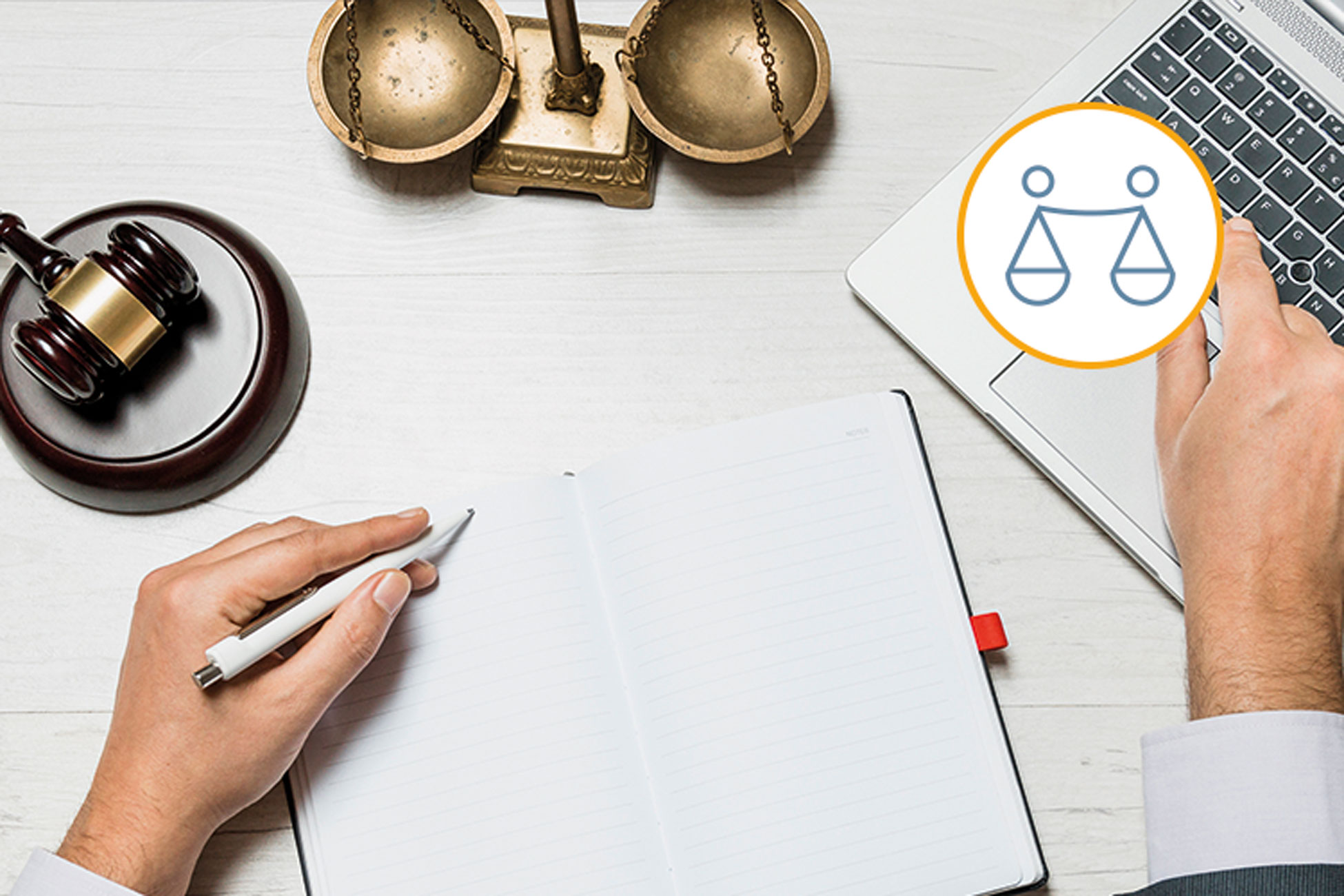 Eine Hand macht handschriftlich Notizen während die andere Hand auf der Tastatur eines Laptops liegt, daneben Hammer und Waage als Symbole der Justiz.