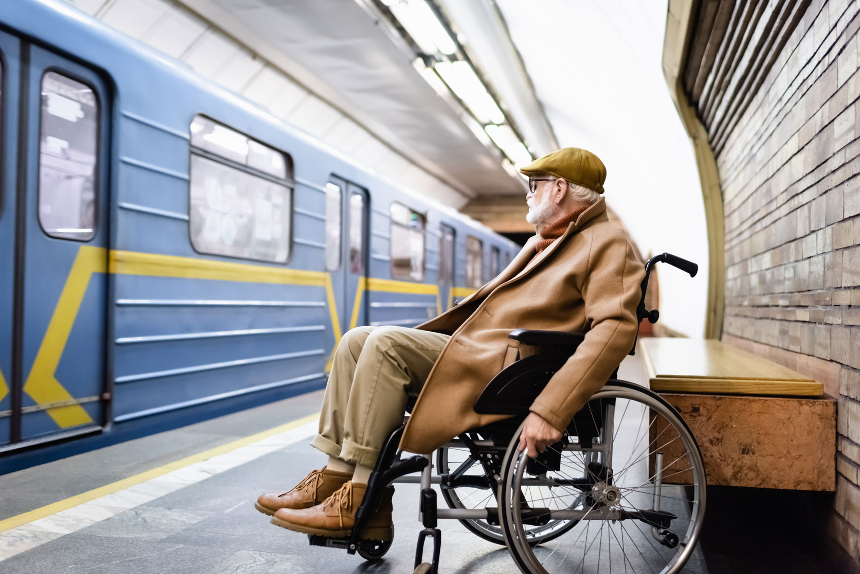 Une personne âgée dans un fauteuil roulant patiente pour monter dans un train